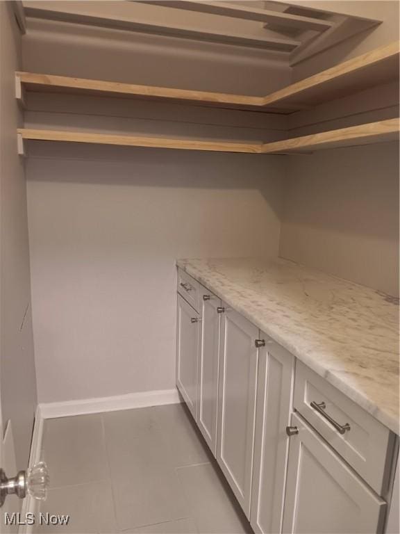 interior space featuring light stone counters, light tile patterned floors, and white cabinets