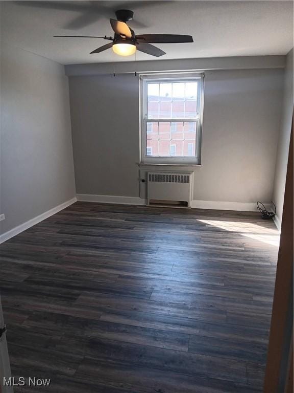 spare room with radiator, ceiling fan, and dark hardwood / wood-style floors