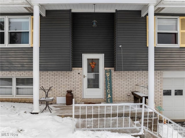 snow covered property entrance with a garage