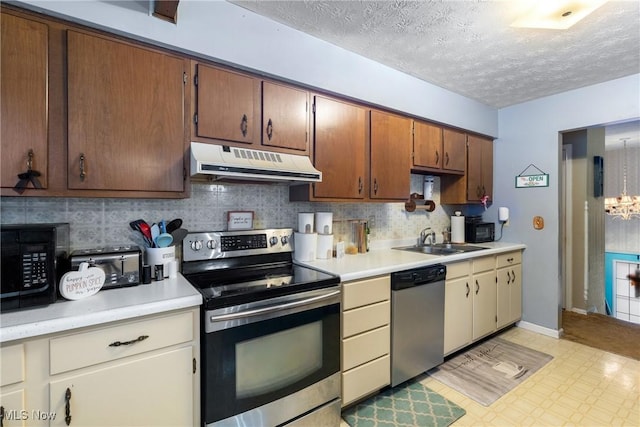 kitchen featuring backsplash, sink, an inviting chandelier, stainless steel appliances, and a textured ceiling