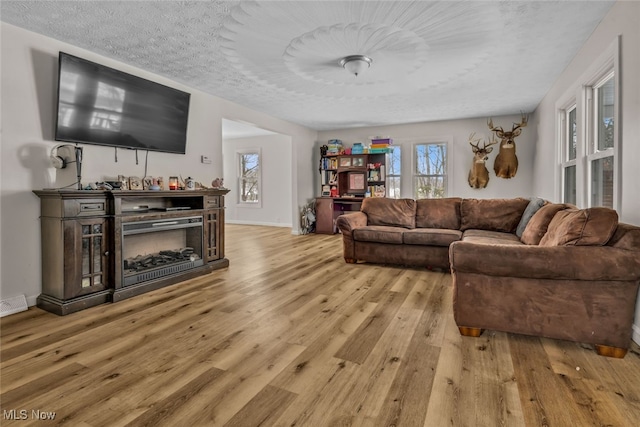 living room featuring light wood-type flooring and a textured ceiling