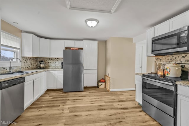 kitchen featuring appliances with stainless steel finishes, white cabinetry, tasteful backsplash, and sink