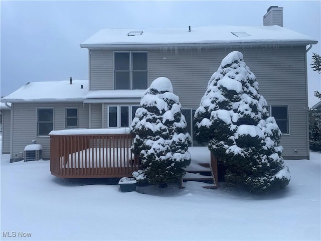 snow covered house with central AC unit and a deck