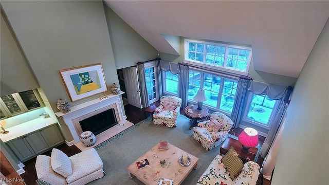 living room featuring a fireplace with flush hearth, high vaulted ceiling, and carpet