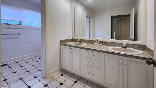 bathroom featuring double vanity, baseboards, tile patterned floors, and a sink