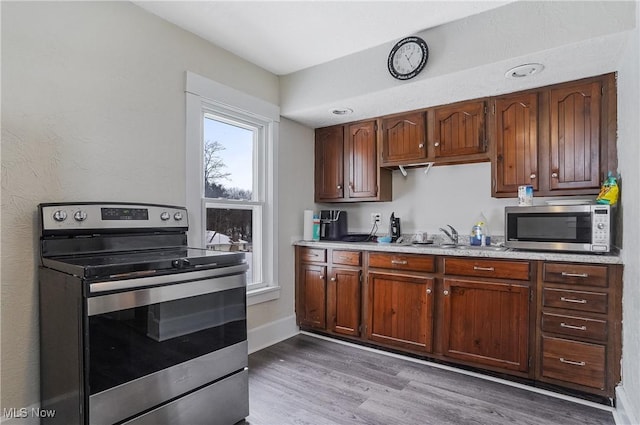 kitchen with stainless steel appliances, light hardwood / wood-style floors, and sink