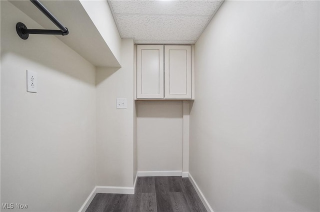 laundry area featuring dark wood-type flooring and cabinets