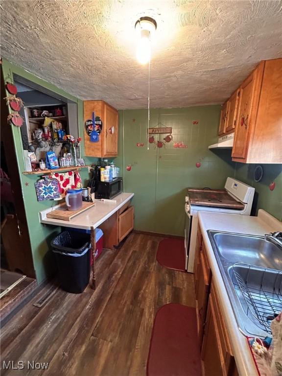 kitchen featuring white range oven, dark wood-type flooring, a textured ceiling, and sink