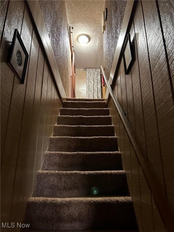 staircase featuring a textured ceiling