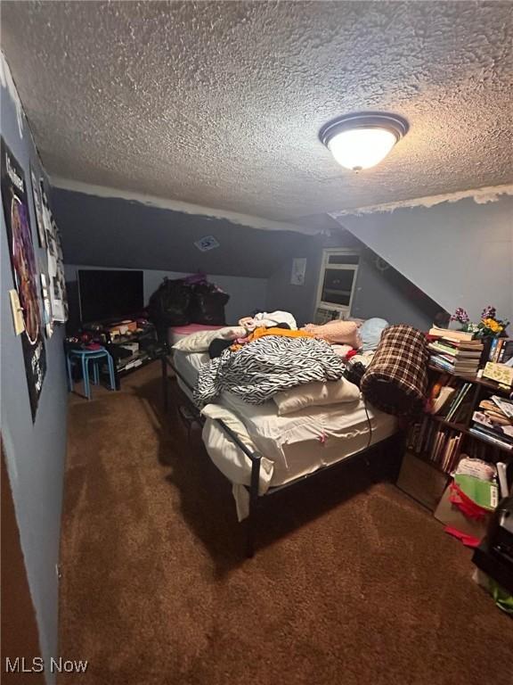 bedroom with lofted ceiling, a textured ceiling, and carpet flooring