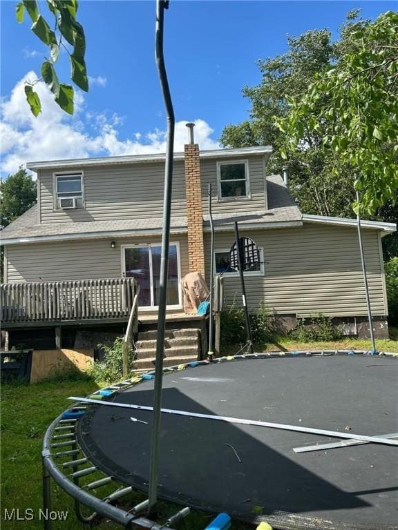 back of property with a trampoline and a deck