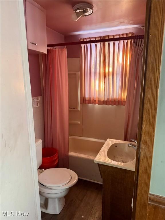 full bathroom with hardwood / wood-style flooring, toilet, vanity, and shower / bath combination with curtain