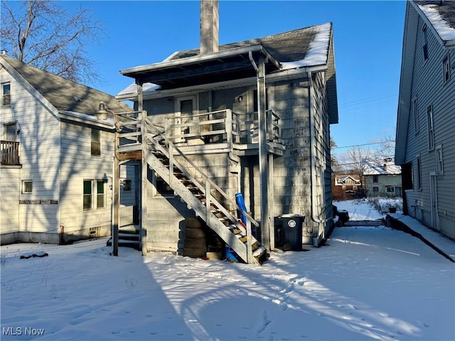 snow covered rear of property with a balcony