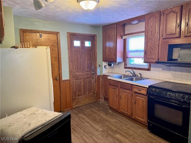 kitchen with a textured ceiling, white fridge, sink, black electric range oven, and light wood-type flooring