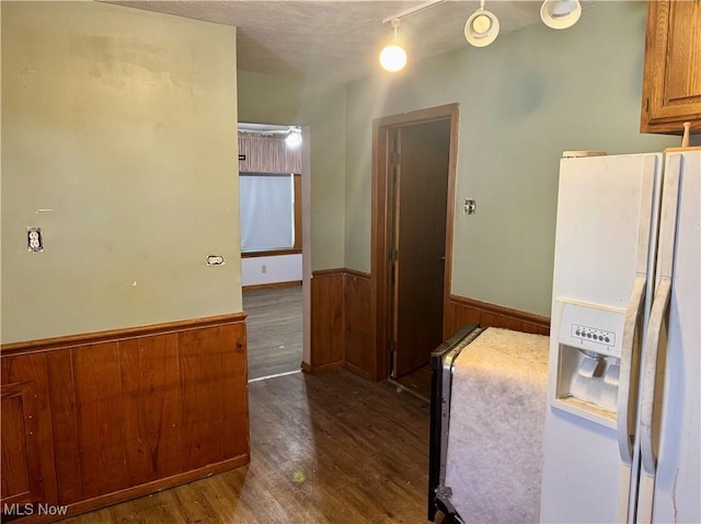 kitchen featuring white refrigerator with ice dispenser, dark hardwood / wood-style flooring, and wood walls