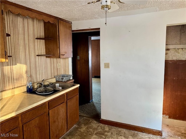 kitchen with ceiling fan, sink, and a textured ceiling