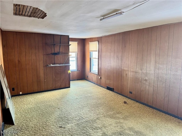 carpeted empty room featuring wooden walls