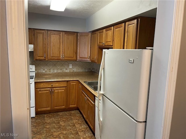 kitchen with sink, white appliances, a textured ceiling, and tasteful backsplash