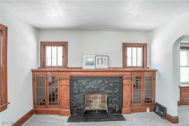 living room featuring light carpet, a stone fireplace, and a textured ceiling