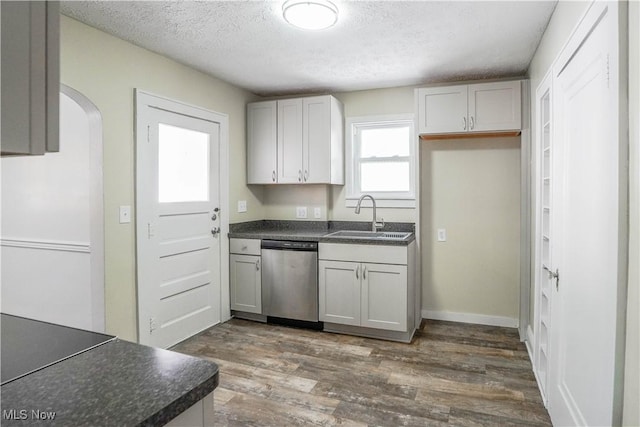 kitchen with white cabinetry, dark hardwood / wood-style flooring, a textured ceiling, stainless steel dishwasher, and sink