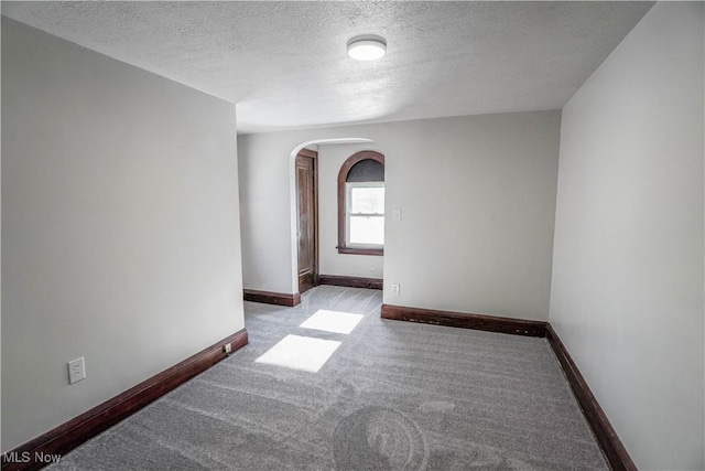 spare room featuring a textured ceiling and light colored carpet