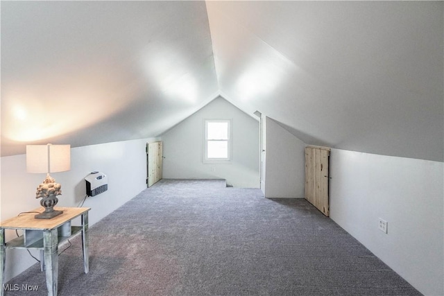 additional living space with carpet floors, vaulted ceiling, and heating unit