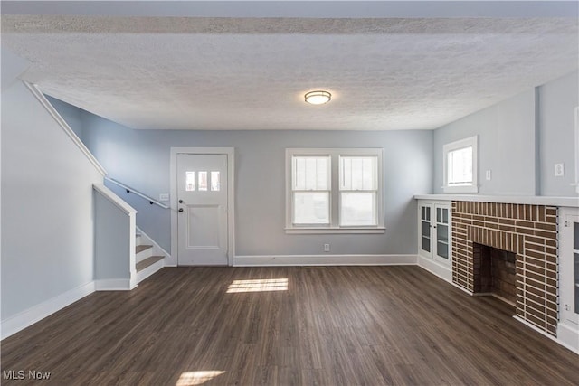 unfurnished living room featuring dark wood-type flooring, a fireplace, and a textured ceiling