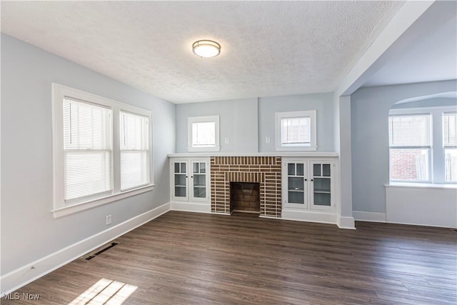 unfurnished living room featuring a fireplace, a textured ceiling, and dark hardwood / wood-style floors