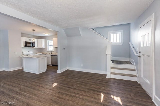 unfurnished living room with a textured ceiling, dark wood-type flooring, and sink