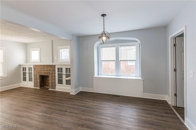 unfurnished living room with a brick fireplace and dark wood-type flooring