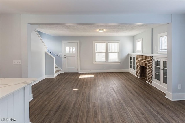 unfurnished living room featuring plenty of natural light, dark hardwood / wood-style floors, and a fireplace