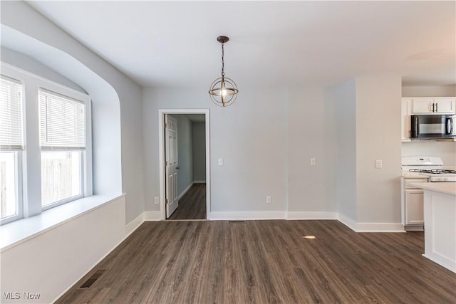 unfurnished dining area featuring dark wood-type flooring and a notable chandelier