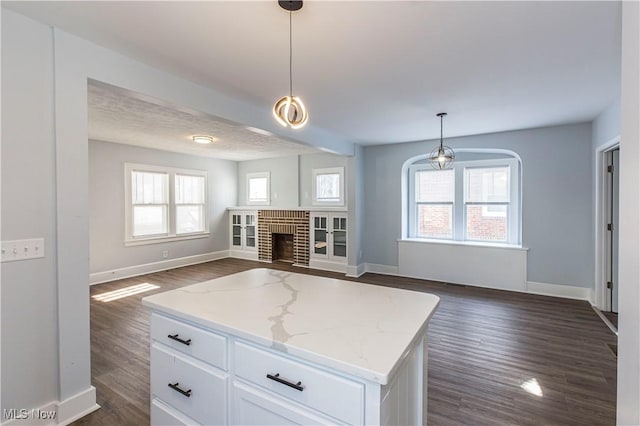 kitchen with white cabinetry, light stone countertops, hanging light fixtures, and a center island