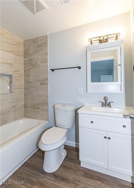 full bathroom featuring wood-type flooring, toilet, vanity, and tiled shower / bath combo