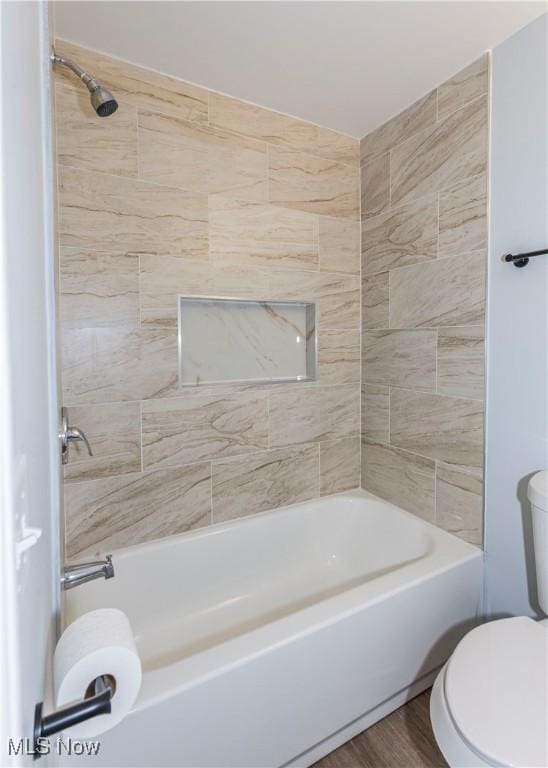 bathroom with toilet, tiled shower / bath, and hardwood / wood-style flooring