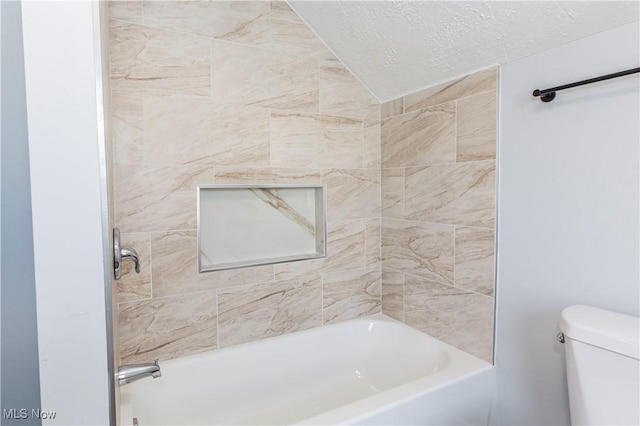 bathroom with toilet, tiled shower / bath combo, and a textured ceiling