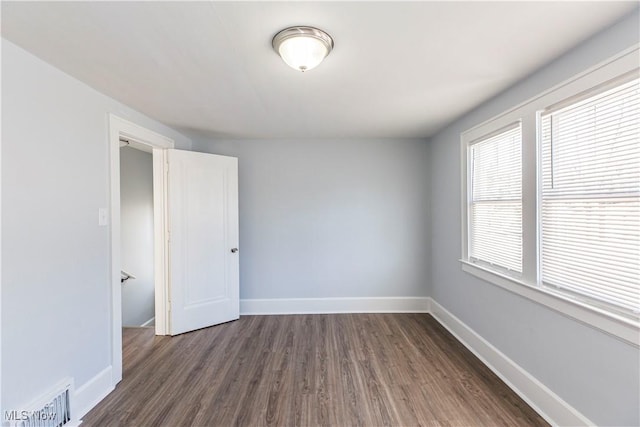 empty room featuring dark hardwood / wood-style flooring and a healthy amount of sunlight