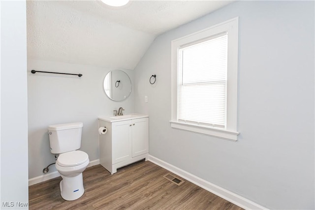 bathroom with vaulted ceiling, toilet, a textured ceiling, and vanity