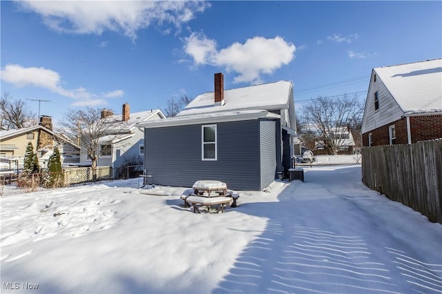 snow covered rear of property featuring an outdoor fire pit