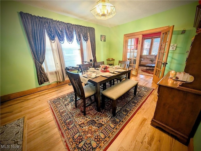 dining room featuring hardwood / wood-style flooring, french doors, and a chandelier