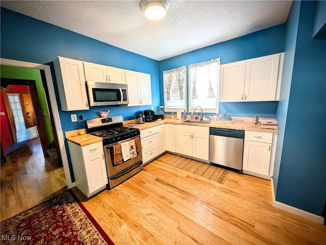 kitchen featuring white cabinets, a textured ceiling, and appliances with stainless steel finishes