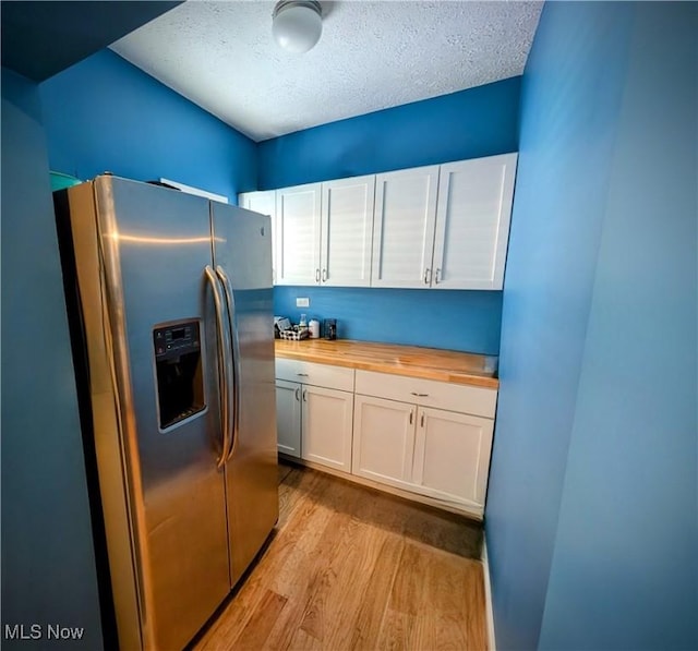 kitchen with a textured ceiling, white cabinetry, stainless steel fridge with ice dispenser, butcher block countertops, and light hardwood / wood-style flooring