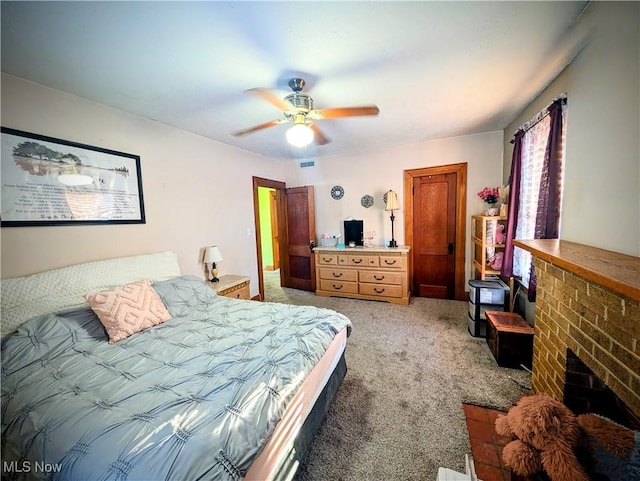 carpeted bedroom with ceiling fan and a fireplace