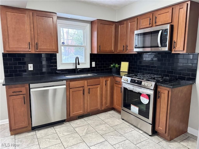 kitchen with backsplash, appliances with stainless steel finishes, and sink