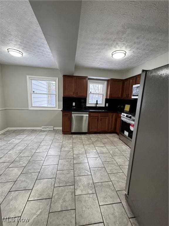 kitchen featuring a textured ceiling, stainless steel appliances, and sink