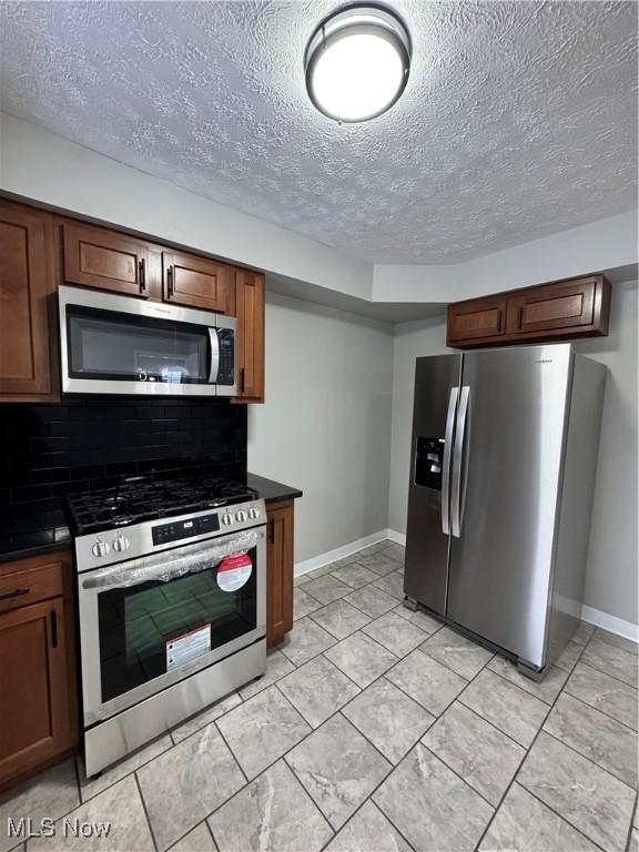 kitchen with tasteful backsplash, stainless steel appliances, and a textured ceiling