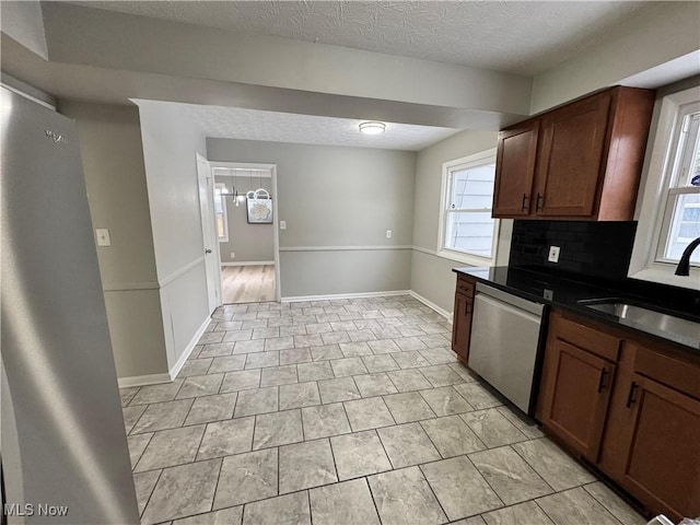 kitchen with a textured ceiling, decorative backsplash, dishwasher, and sink