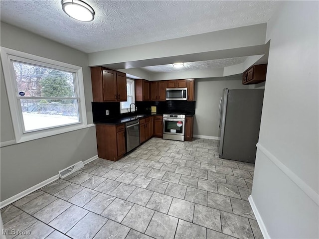 kitchen featuring decorative backsplash, appliances with stainless steel finishes, sink, and a textured ceiling