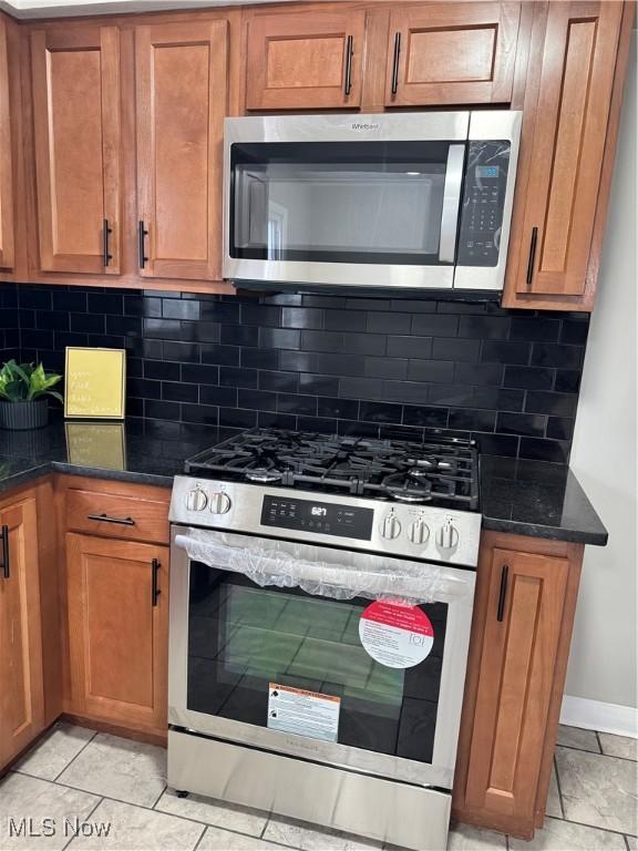 kitchen featuring light tile patterned flooring, stainless steel appliances, and tasteful backsplash