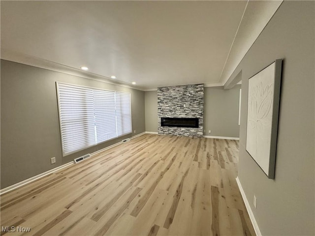 unfurnished living room featuring light wood-type flooring and a stone fireplace